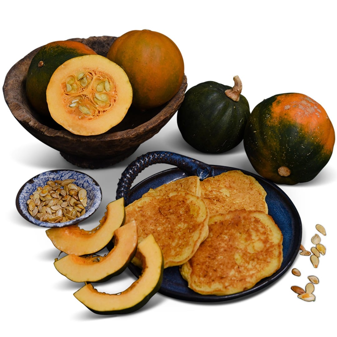 Cut and whole Sweetnut Winter Squash with squash pancakes and seeds on a white background.