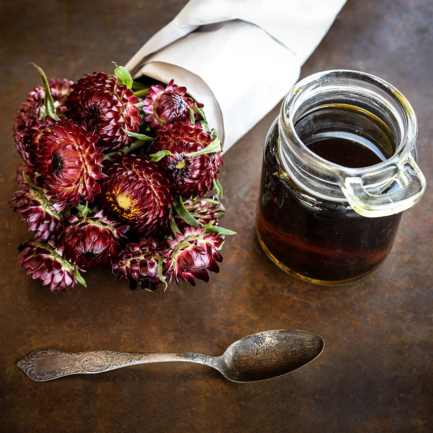 King Size Red Strawflowers with some strawflower tea and spoon on a copper background.
