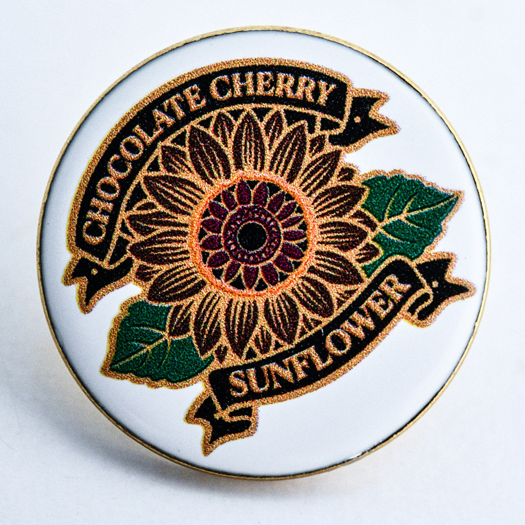 A close-up macro view of Chocolate Cherry Sunflower Limited Edition Pin.