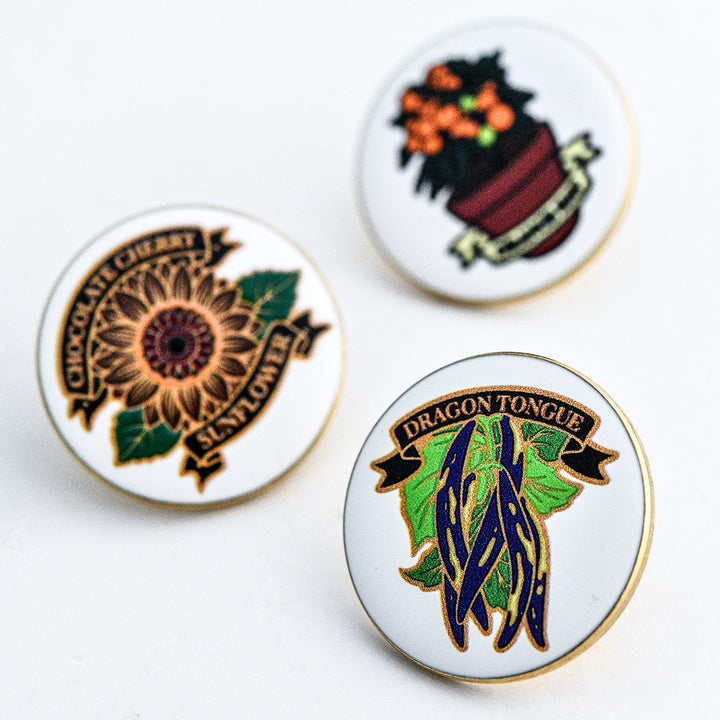 Three Limited Edition Pins showing the Dragon Tongue Bean Limited Edition Pin in the foreground on a white background.