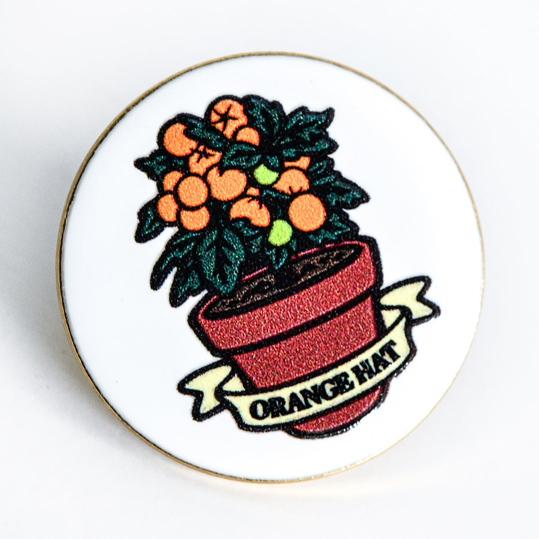 A close-up macro view of Orange Hat Tomato Limited Edition Pin on a white background.