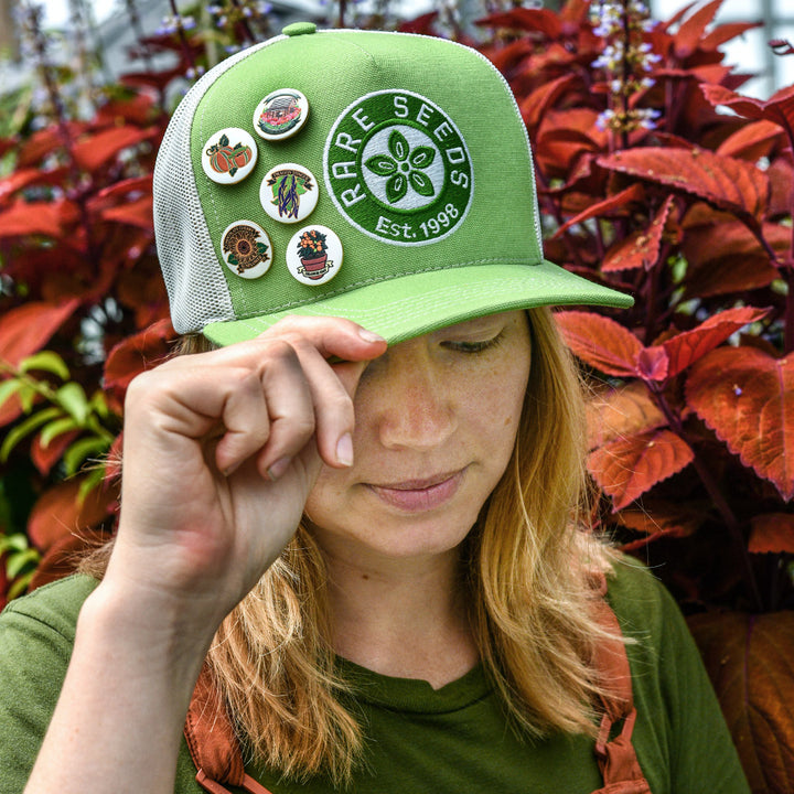 A Baker Creek employee shows off all the Limited Edition Pins on a Baker Creek Hat.