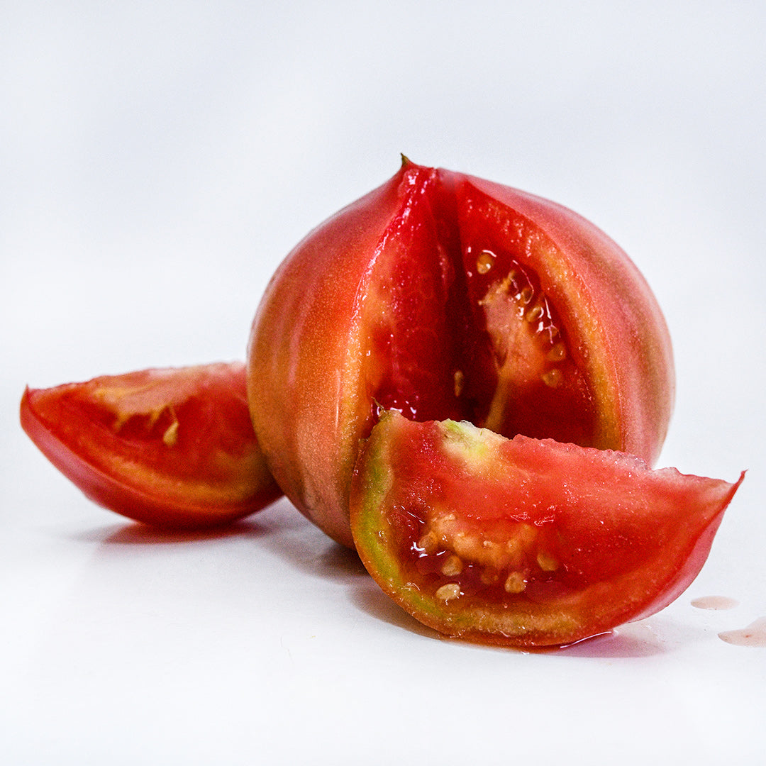 A single sliced Aichi First Tomato on a white background.