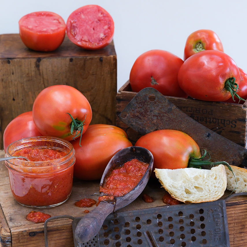 Amish Paste Tomatoes processed as paste in a jar and spoon arrange on wooden boxes.