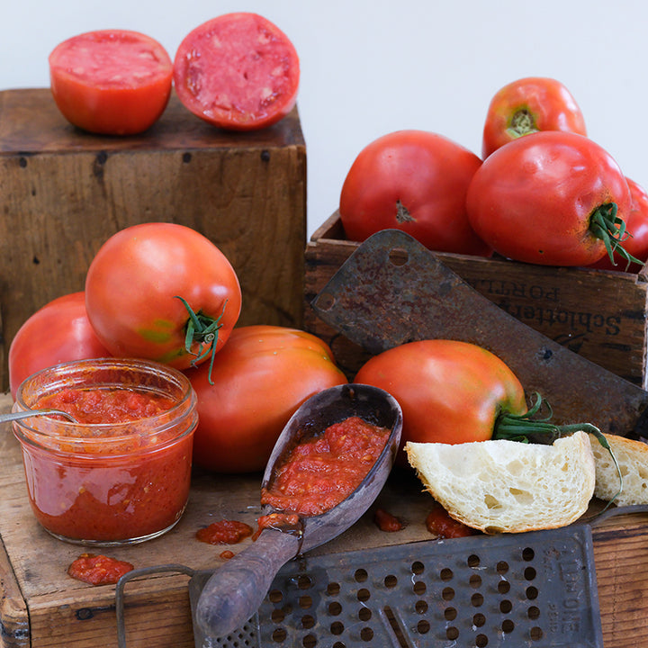 Amish Paste Tomatoes processed as paste in a jar and spoon arrange on wooden boxes.
