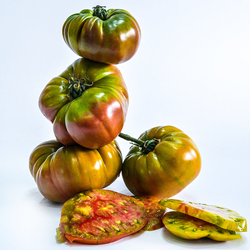 Ananas Noire or Black Pineapple Tomatoes stacked in a tower on a white seamless background.