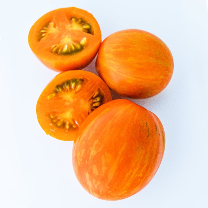 Whole and cut Apricot Zebra Tomatoes on white background.