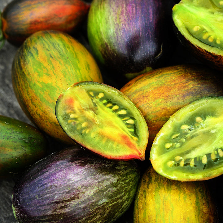 Close-up of a pile of cut and whole technicolor Brad's Atomic Grape Tomatoes.