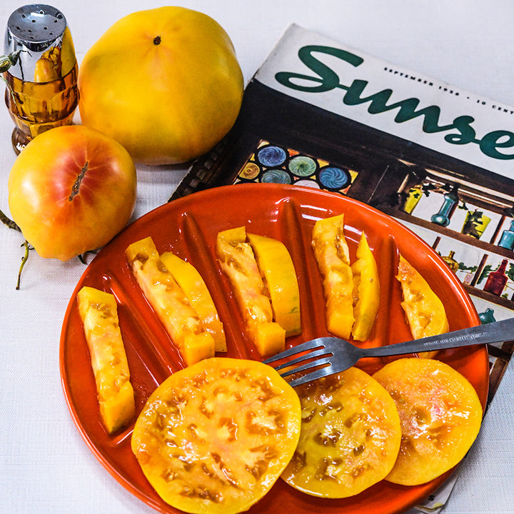 Big Rainbow Tomatoes on a red plate with a vintage Sunset magazine and salt shaker.