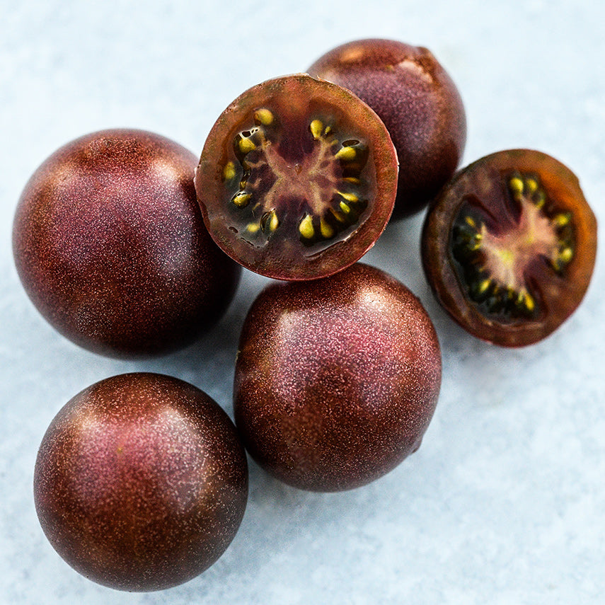Close-up of several Black Cherry Tomatoes on a light background.