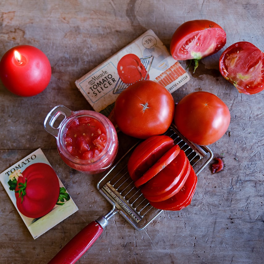 Whole, sliced and cut Bonnie Best Tomatoes on a cutting board with some in a jar.
