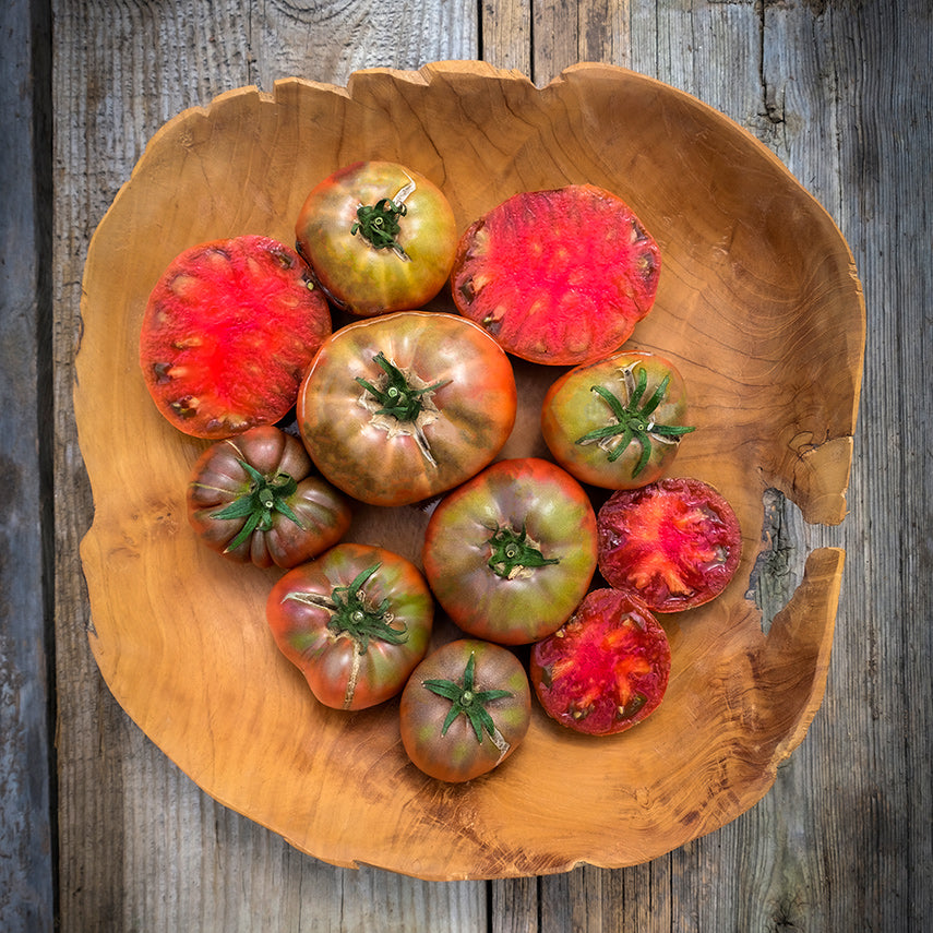 Cut and whole Carbon Tomatoes arranged on a wooden platter. Image by Lucy Hutchins.