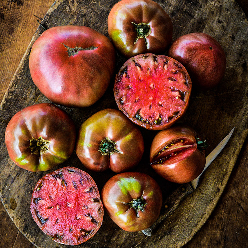 Carbon Tomatoes arranged on a wooden cutting board with a knife.