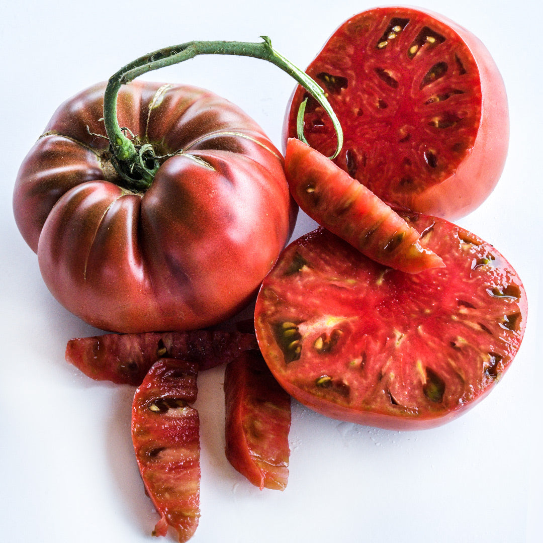 Cut and whole Chocolate Miracle Tomatoes arranged on a white background.