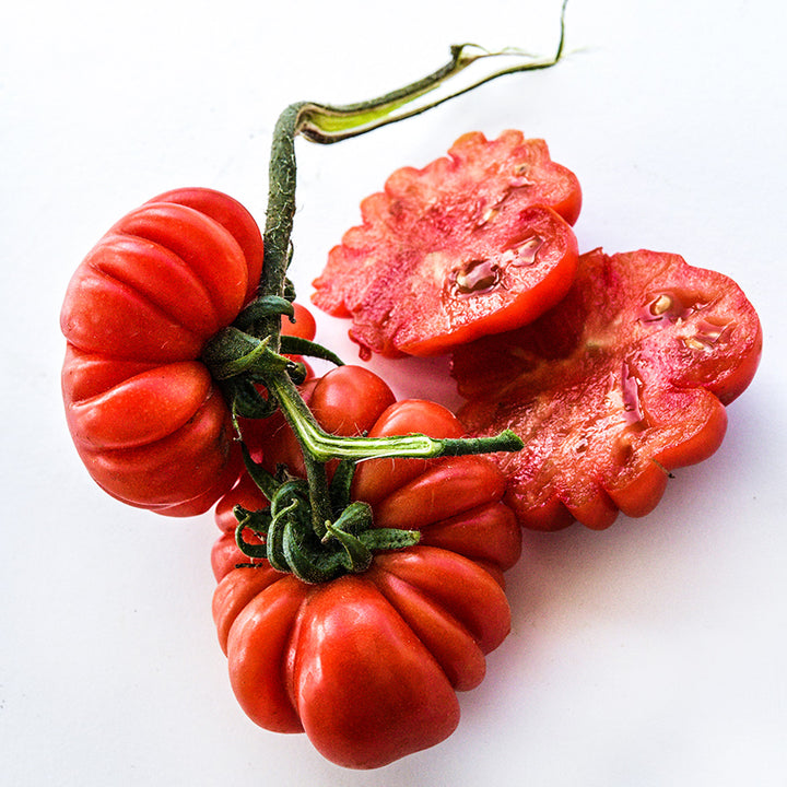 Close-up of cut and whole Costoluto Genovese Tomatoes on high key background.