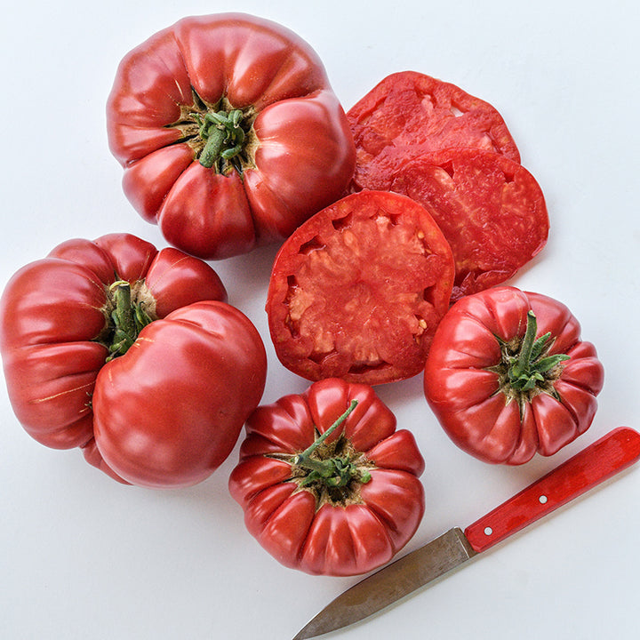 Cut and whole German Pink Tomatoes on light background.