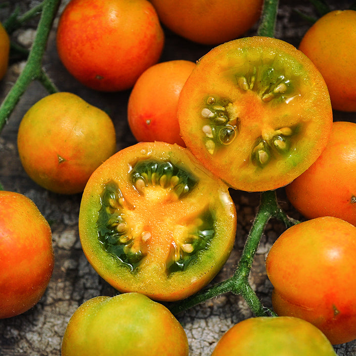 Macro close-up of cut and whole Isis Candy Cherry Tomatoes on a wood background.