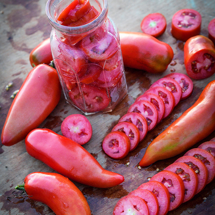 Jersey Devil Tomatoes sliced, whole and in a jar arranged on wooden cutting board.