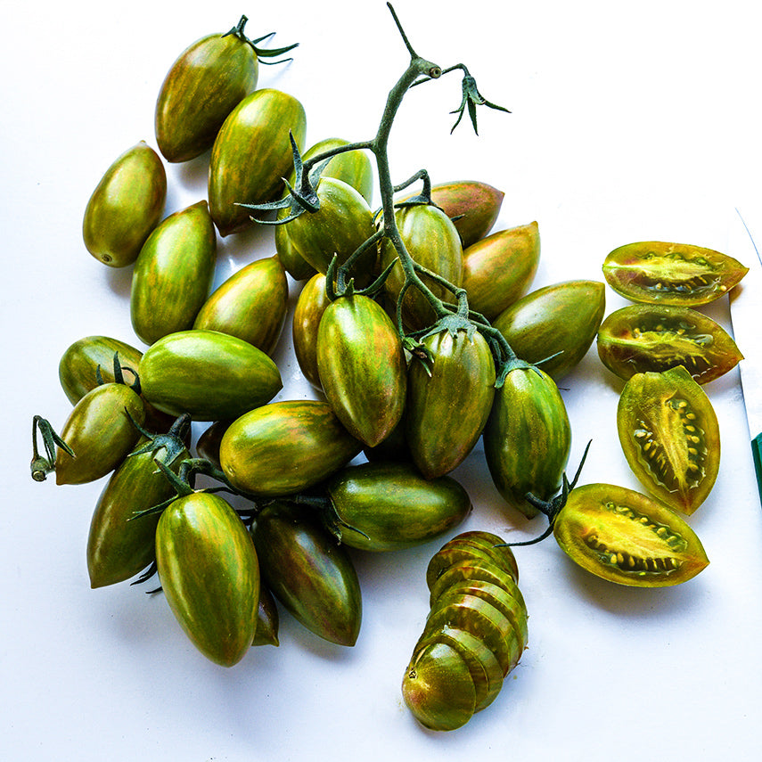 A cluster of whole and cut Lucky Tiger Tomatoes on white background.