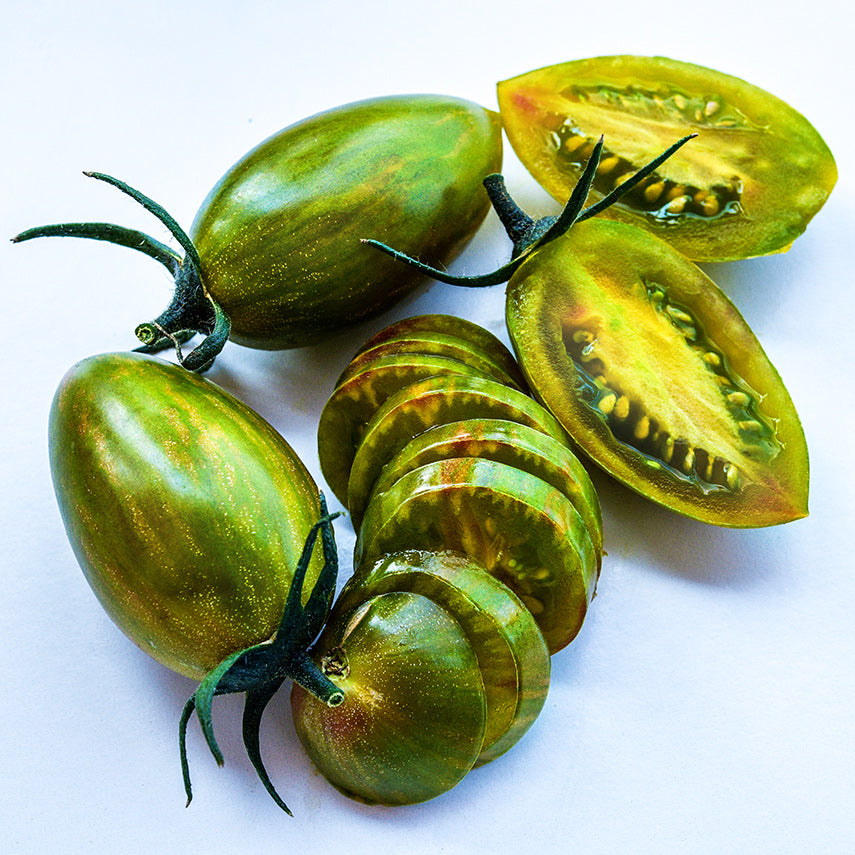 Close-up macro view of whole and sliced Lucky Tiger tomatoes n a white background.