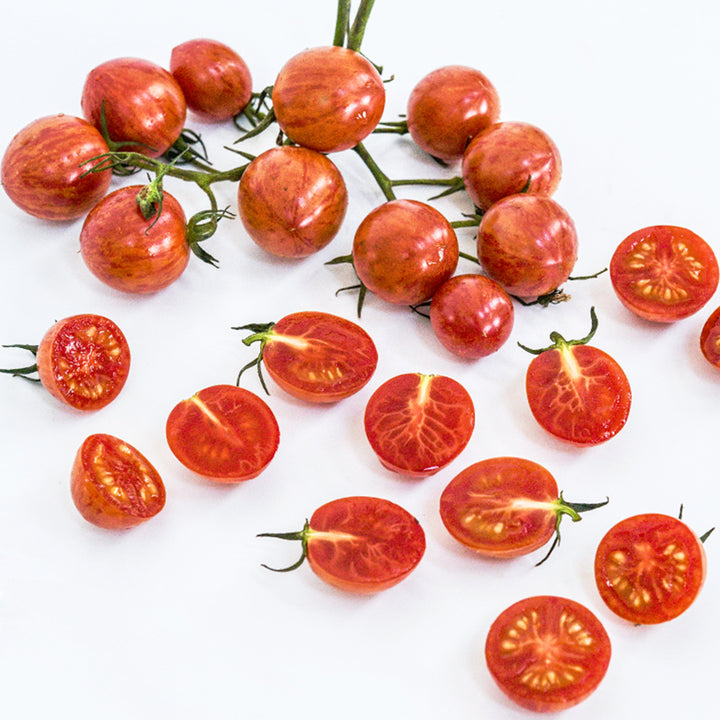 Cut and whole Pink Bumble Bee Tomatoes arranged on a white background.