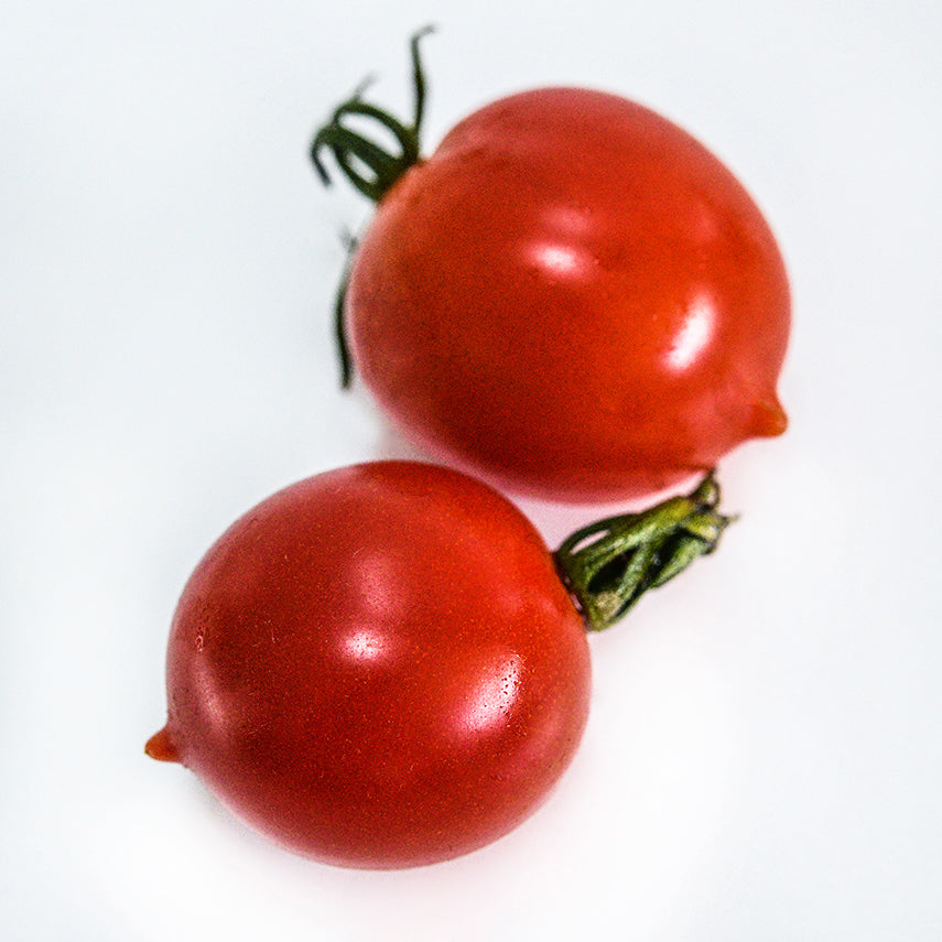 A close-up macro of a couple of Riesentraube Tomatoes on bright white background.
