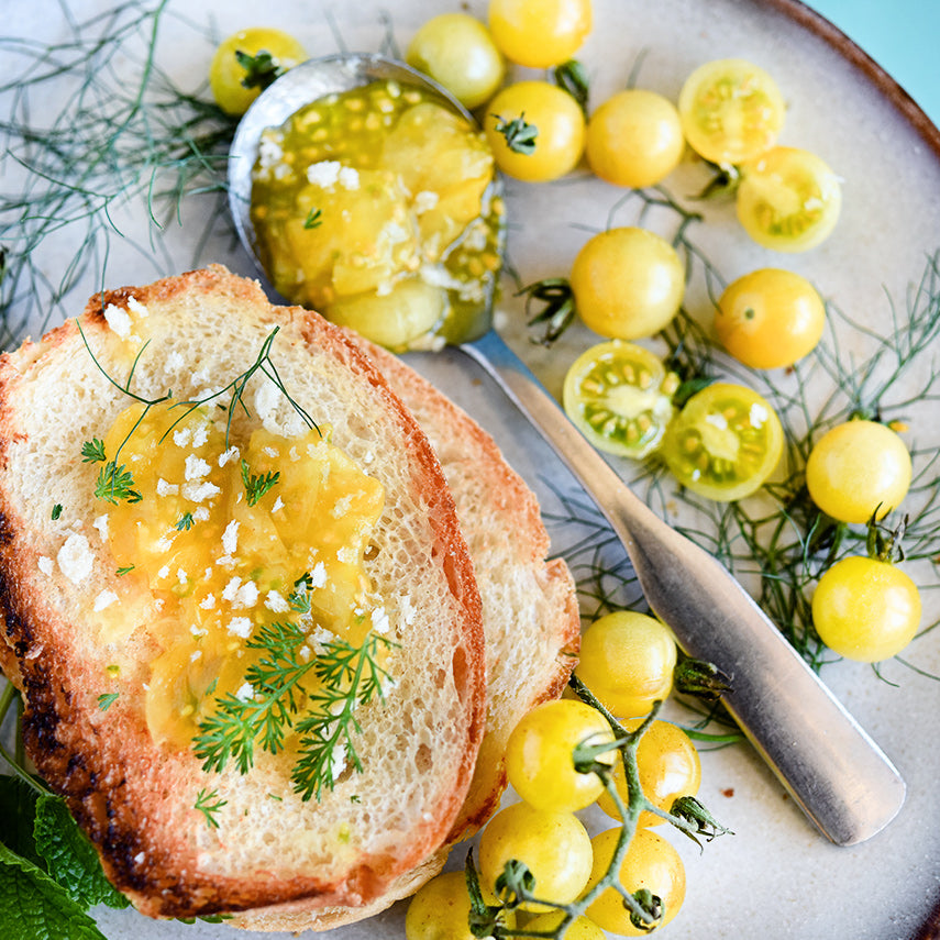 A plate with toast and White Currant Tomato jam with tomatoes and dill.