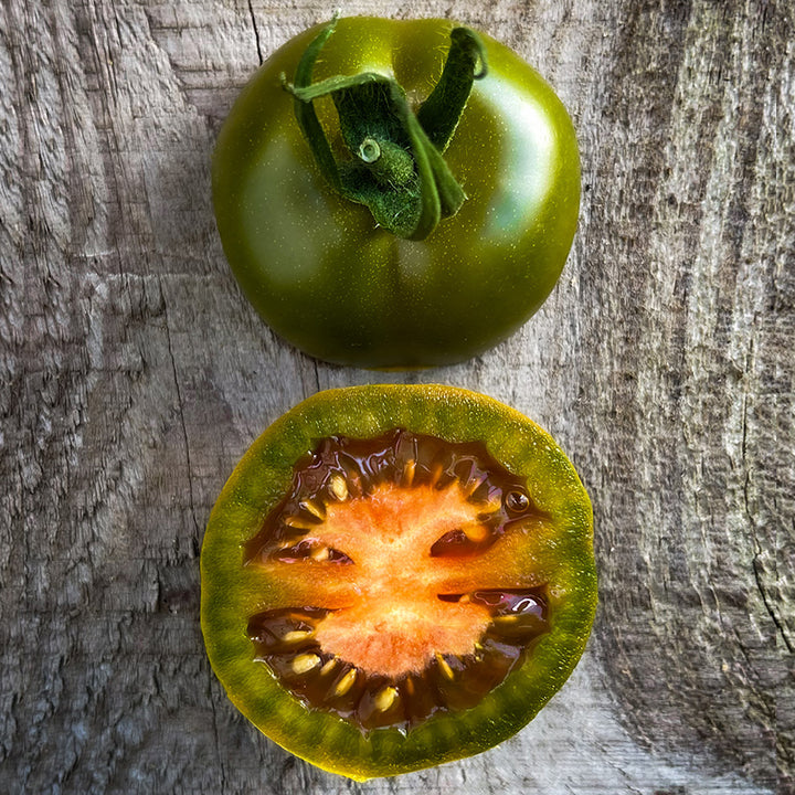 A close-up macro view of a halved Evil Olive Tomato on a wooden background.