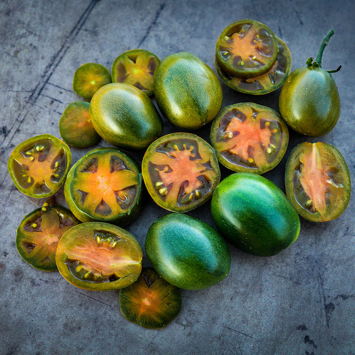 Cut and whole Evil Olive Tomatoes arranged in a pleasant display on brown rustic background.