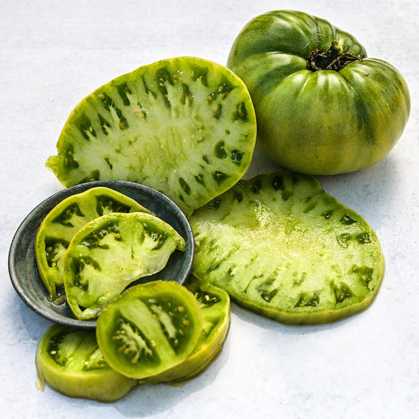 Sliced and whole Green Giant Tomatoes on white background.