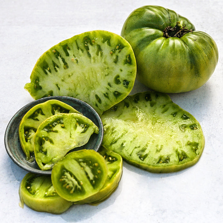 Sliced and whole Green Giant Tomatoes on white background.