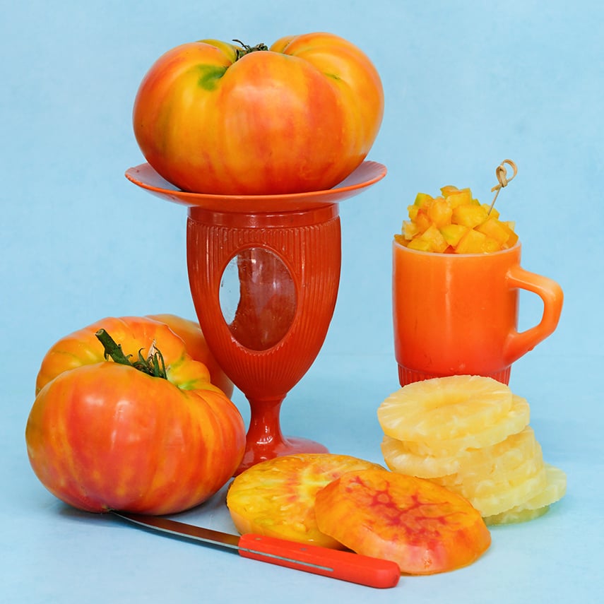 Pineapple Tomatoes on orange plates with pineapple slices on light blue background.