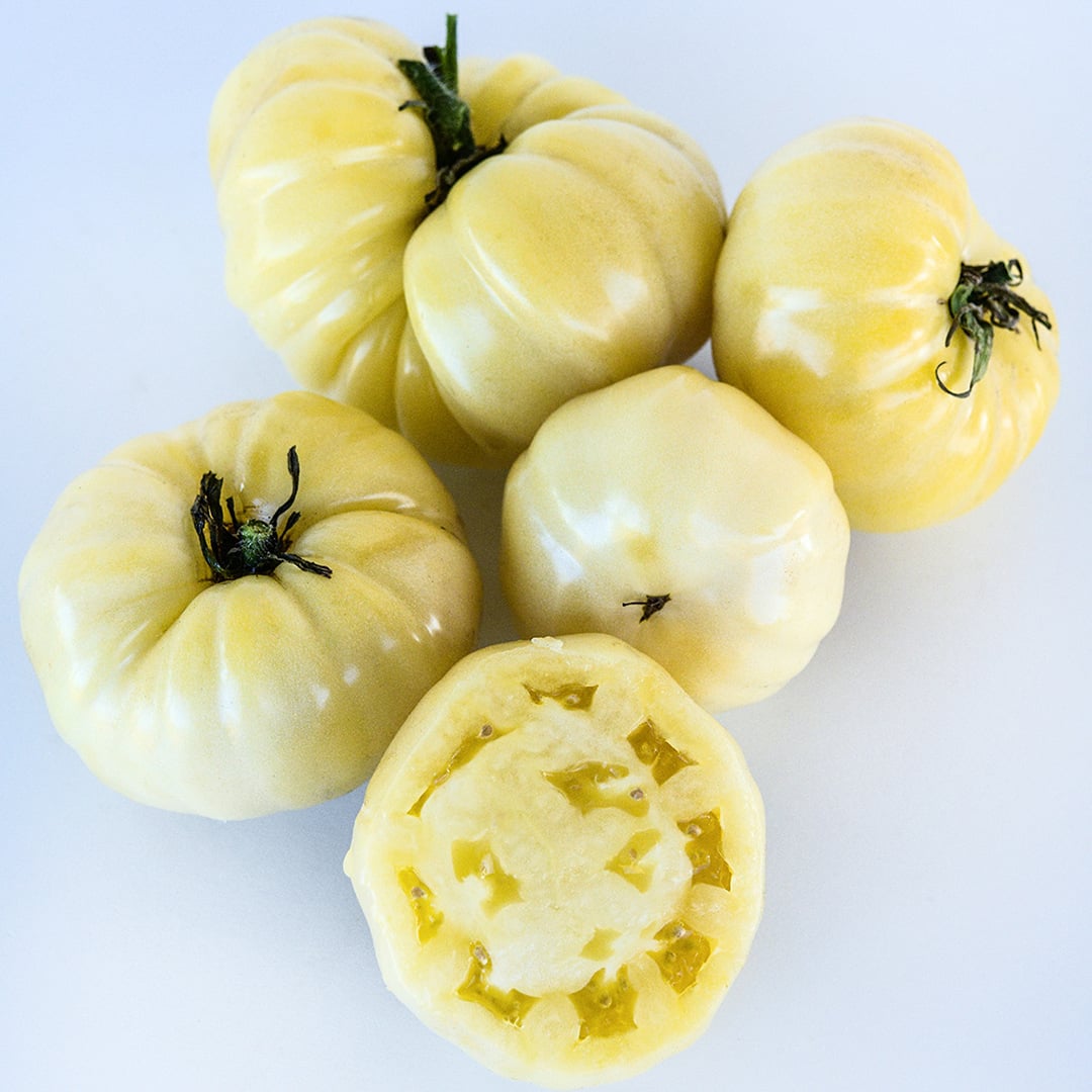 Cut and whole White Beauty or Snowball Tomatoes on a white background.