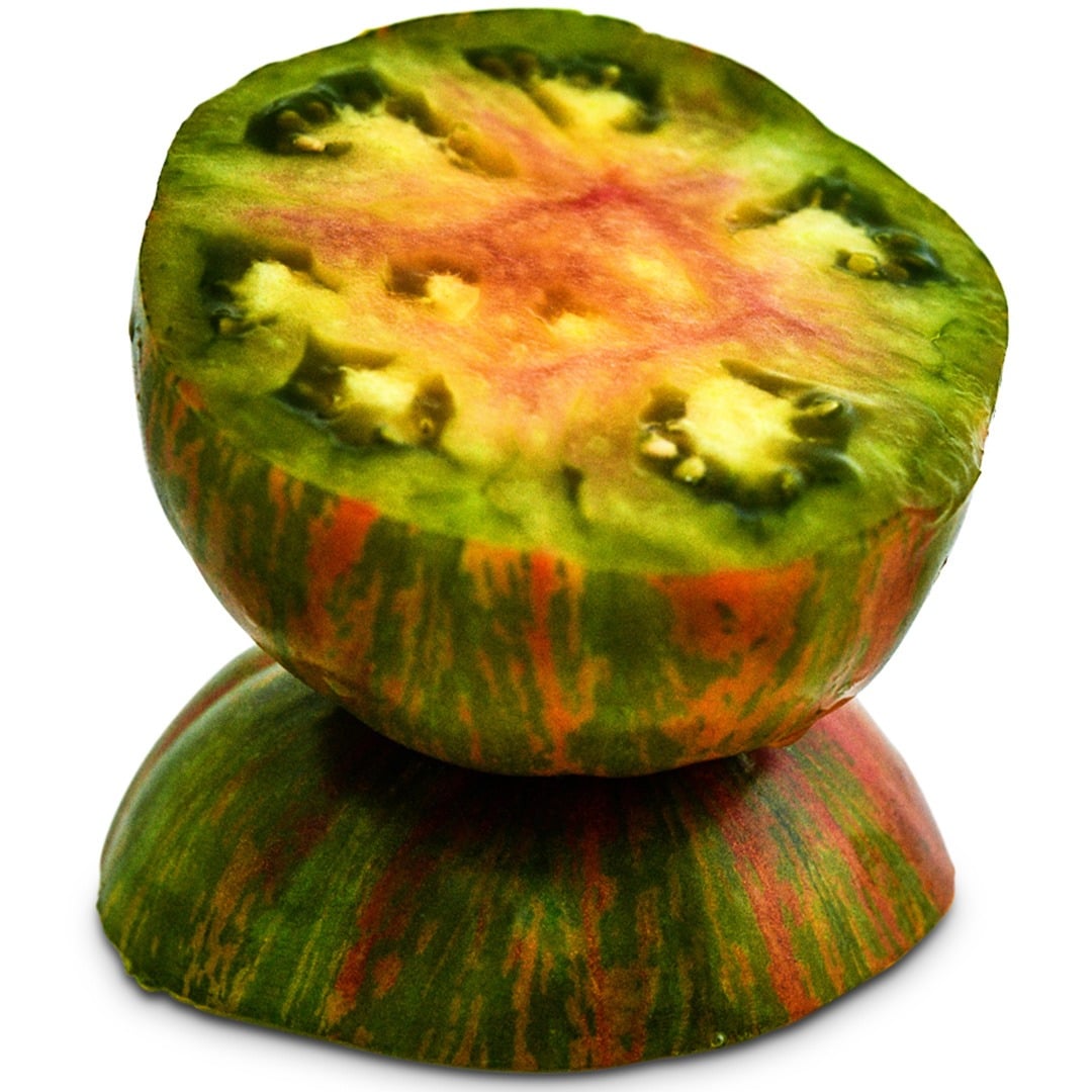 A single Berkeley Tie-Dye Green Tomato sliced in half and then stacked on a white background.
