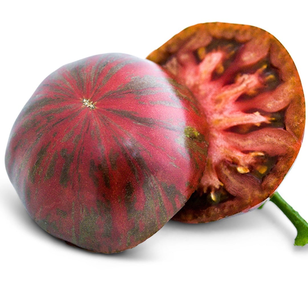 A single Berkeley Tie-Dye Pink Tomato sliced in half on a white background.