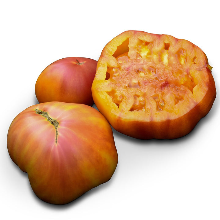 Two whole Big Rainbow tomatoes and one cut in half to show the center on a white background.