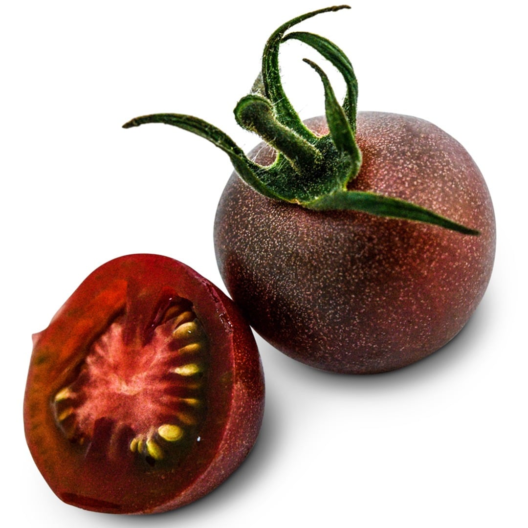 One whole and one sliced Black Cherry Tomato on a white background.
