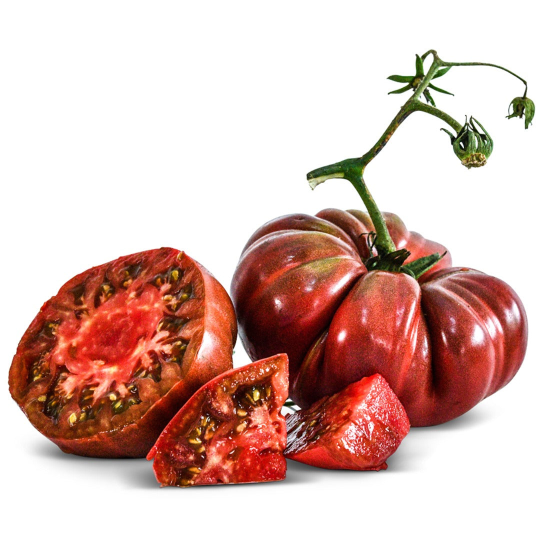 One whole and one cut Black from Tula Tomato on a white background.