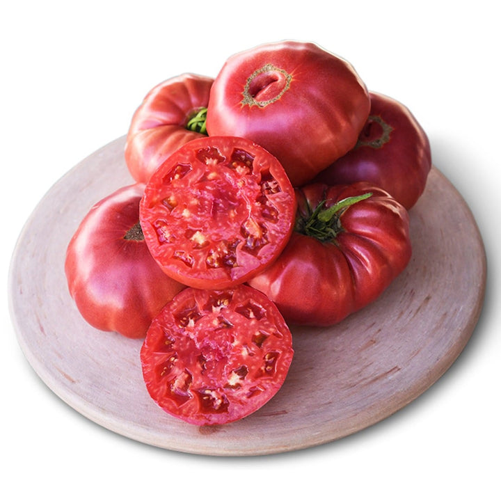 Granny Cantrell German Red Tomatoes stacked on a wooden plate with a white background.