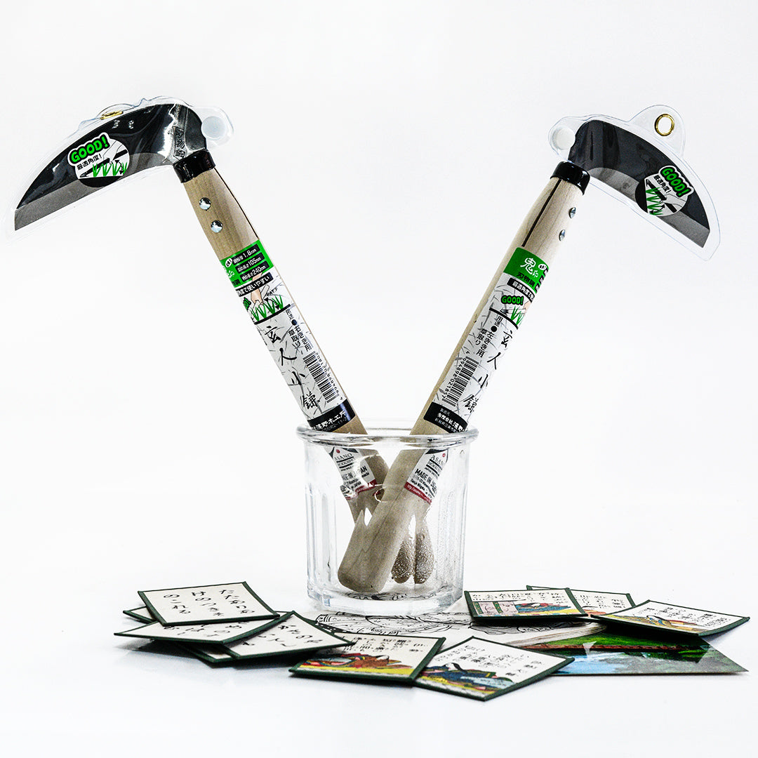 Professional Sickle Right and Left Handed Tools in a glass with Japanese cards on light background.