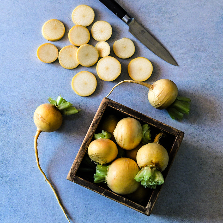 Sliced Aji Kogane Turnips cascade down to whole turnips and then graduate to a box of four whole turnips.