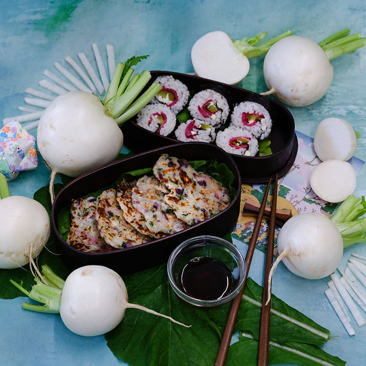 Miyama Turnips, sushi and turnip pancakes with sauce on light blue background.
