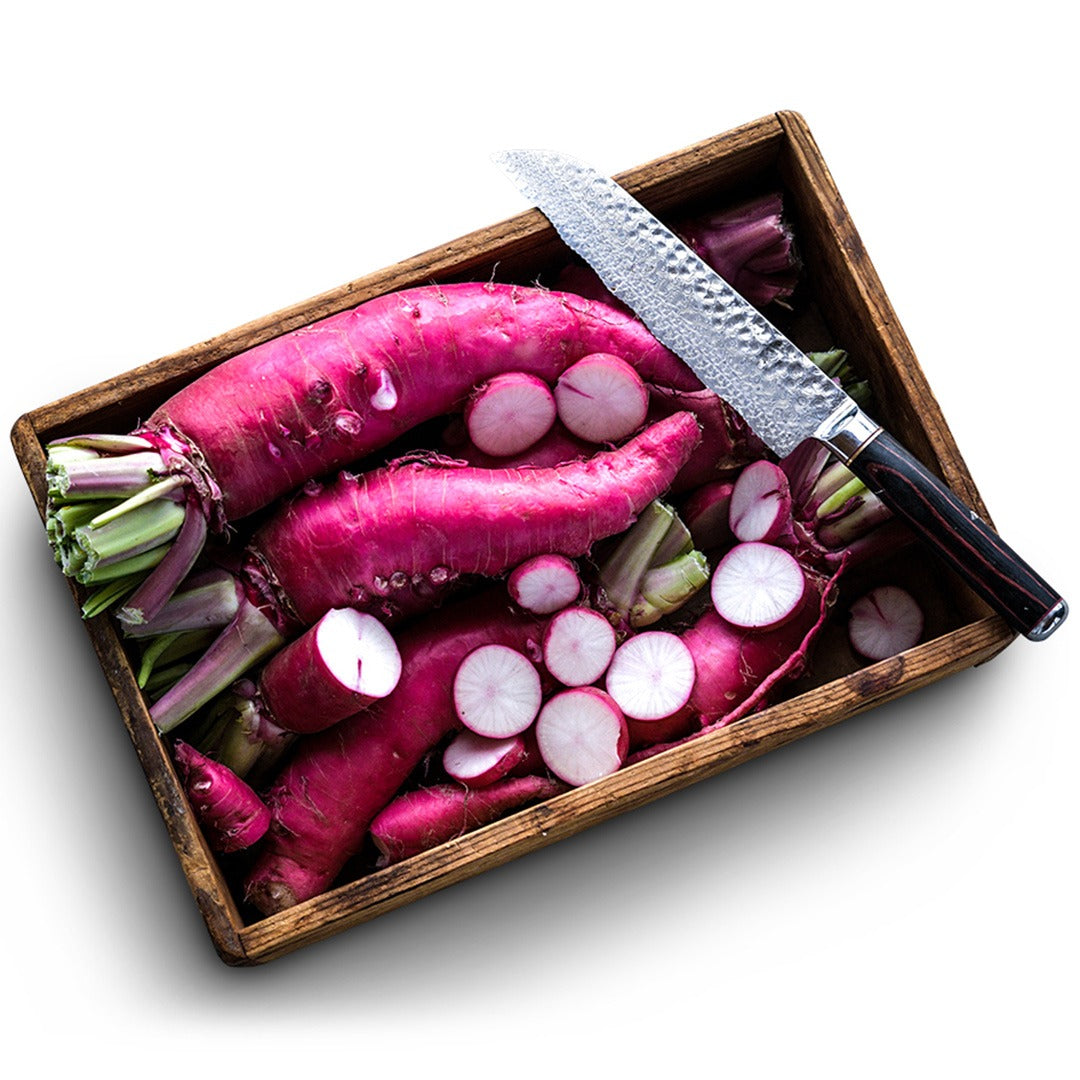 Wooden crate with whole and sliced Asuka Akane Turnips with a knife on a white background.