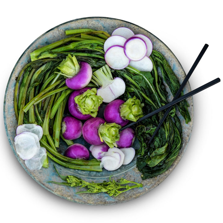 Nagasaki Akari Kabu Turnips with sauteed greens plated in a ceramic bowl on a white background.
