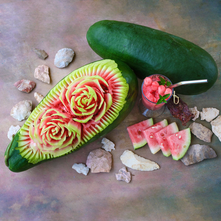 Art Combe's Ancient Watermelon with carved flowers and cut melon on a pastel background.
