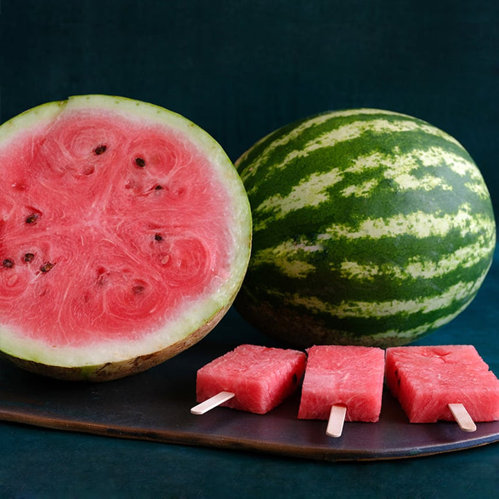 Red flesh Crimson watermelon with watermelon popsicles on a dark blue background.