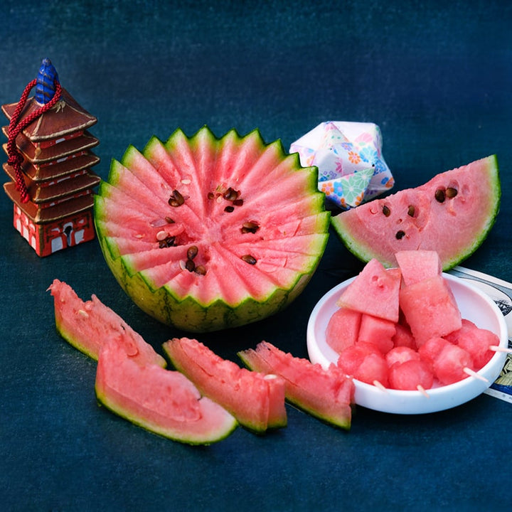 Early Girl (Otome) Watermelon cut on a dark blue background.