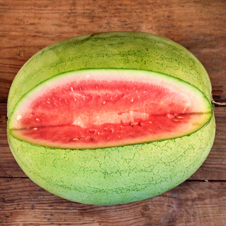 Overhead view of a cut Refined Sugar Watermelon on a wooden table.