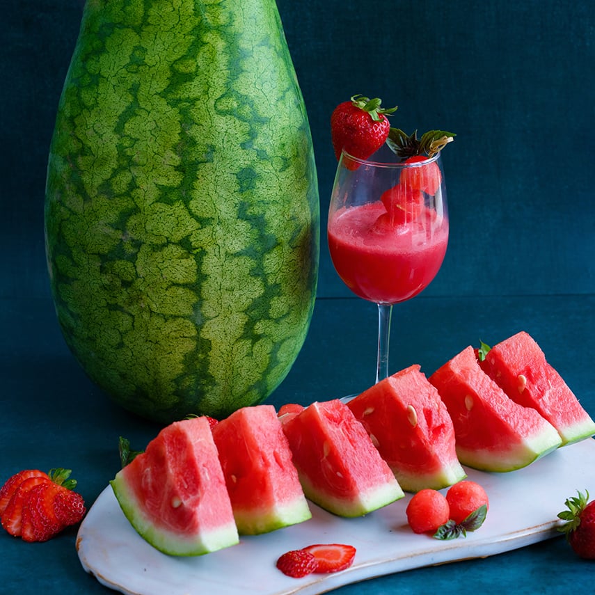 A whole Strawberry Watermelon with slices and watermelon slushie with strawberries.
