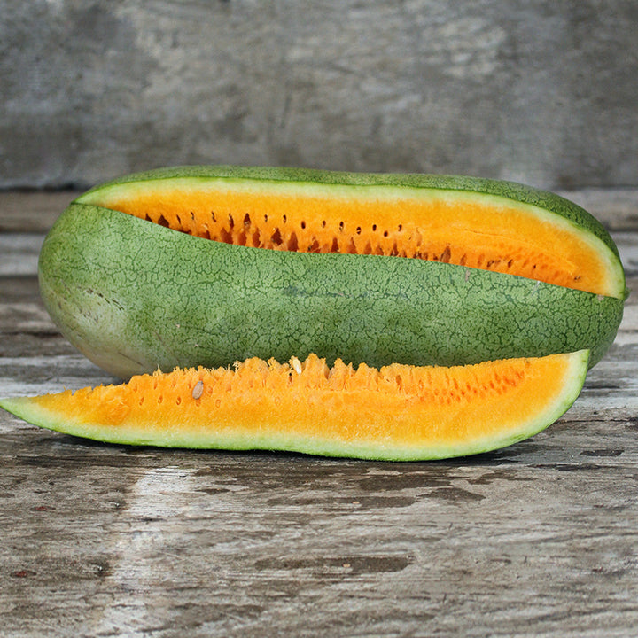 Texas Golden Watermelon with a slice cut out of it on wooden background.